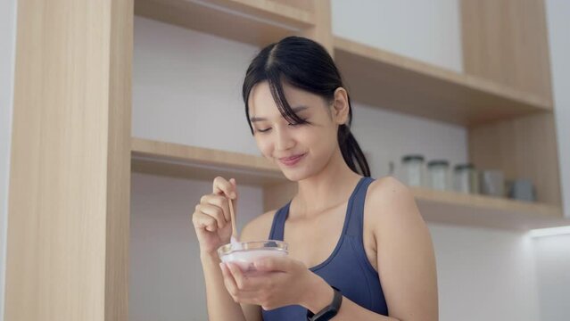 Asian woman eating yogurt in the morning at her home.