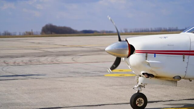 The propeller of a small white aircraft with red lines rotating. Starting the plane before the departure.