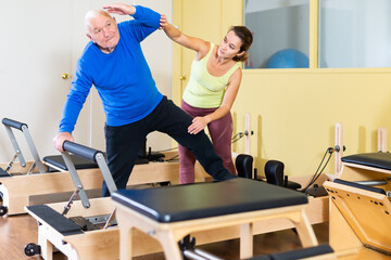 Fototapeta na wymiar Senior man workout in rehabilitation center. Personal trainer helping senior man