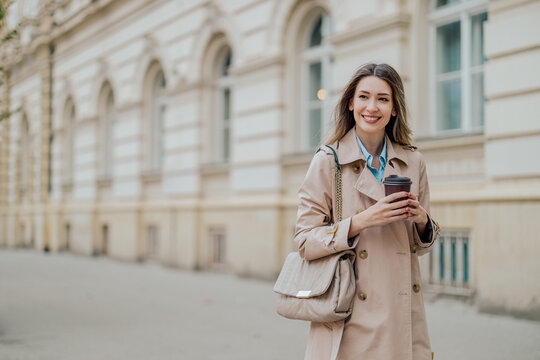 Stylish female walking in the city streets and holding a coffee takeaway