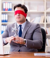 Blindfold businessman sitting at desk in office
