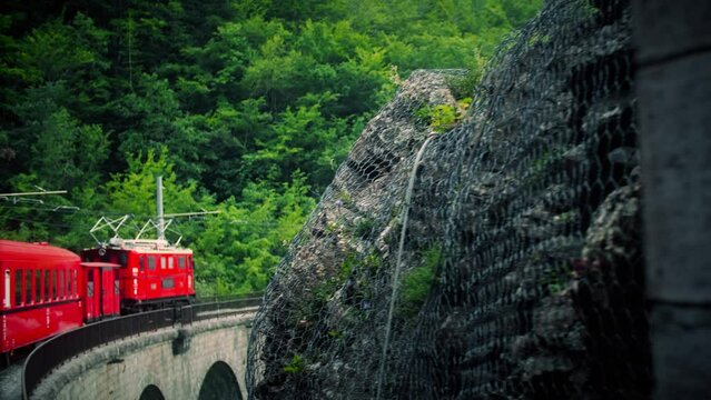 Retro red train moves along an old stone bridge. La Mure, France