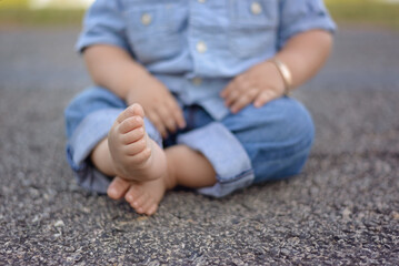 Child in Denim Sitting Barefoot on Pavement
