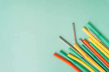 Metal and plastic straws with brushes close-up on green background.