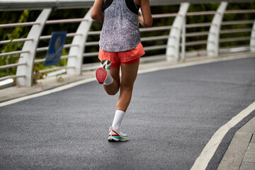 rear view close-up of legs and feet of an asian woman running outdoors on the road