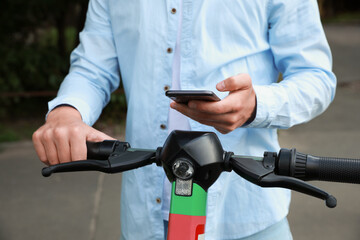 Man using smartphone to pay and unblock electric kick scooter outdoors, closeup