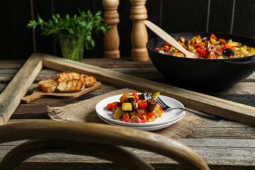 Delicious ratatouille served with bread on wooden table