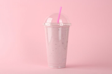 Plastic cup of tasty smoothie on pink background