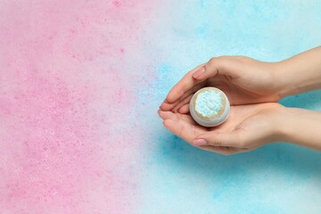Woman holding bath bomb over water with foam, top view. Space for text