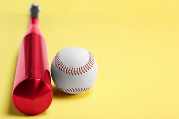 Baseball bat and ball on yellow background, closeup. Space for text