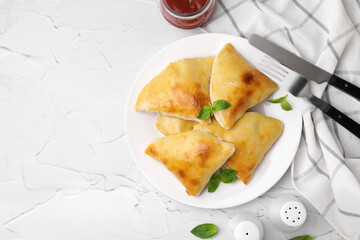 Delicious samosas served on white textured table, flat lay. Space for text