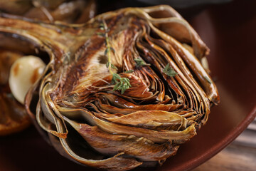 Tasty grilled artichoke on plate, closeup view