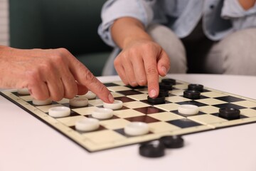 Naklejka premium Women playing checkers at white table, closeup