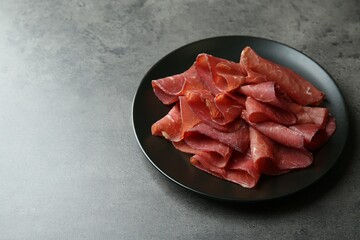 Plate with tasty bresaola on grey table. Space for text