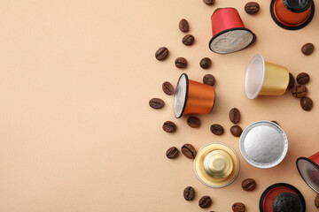 Many coffee capsules and beans on beige background, flat lay. Space for text