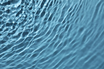Rippled surface of clear water on light blue background, top view