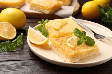 Tasty lemon bars served on wooden table, closeup