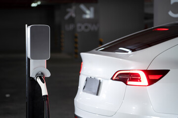 EV electric car recharge at shopping center parking lot charging in downtown city showing urban...