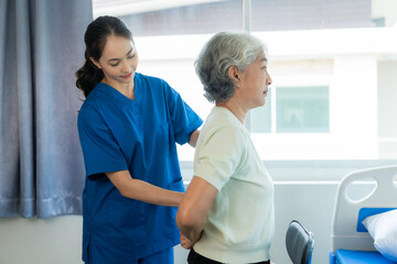 A young Asian nurse at a nursing home takes care of a senior woman. The attending physician...