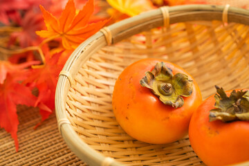 秋に美味しいざるに乗せた柿と紅葉