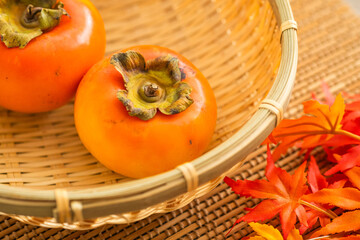 秋に美味しいざるに乗せた柿と紅葉