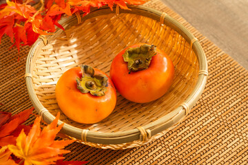 秋に美味しいざるに乗せた柿と紅葉