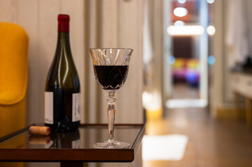 A glass of red wine with bottle put on side table in the house to enjoy and relaxing moment.