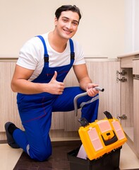 Young repairman working at the kitchen