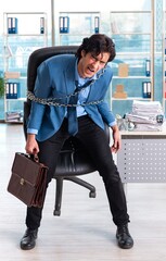 Chained male employee unhappy with excessive work
