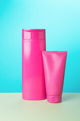 Two tubes of crimson color on a beige turquoise background.