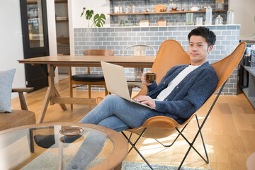 お洒落な部屋で温かいコーヒーを飲みながらくつろぐ男性...