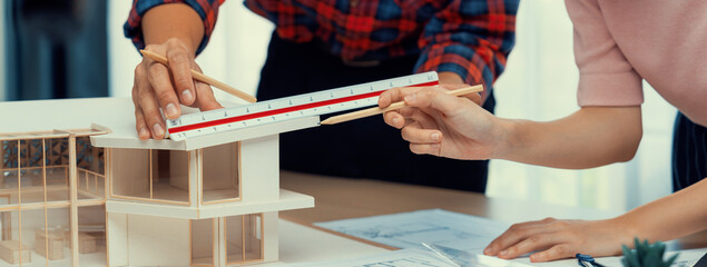 Smart architect engineer and interior designer working together and measuring house model by using...