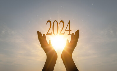 2024 concept: Hands hold 2024 against on sunset background
