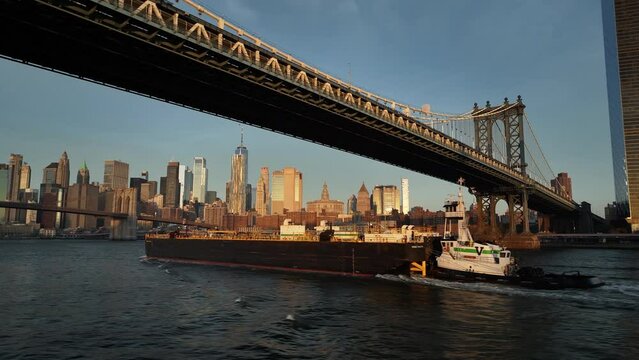 Aerial shot of a barge passing beneath New York City's Manhattan Bridge.