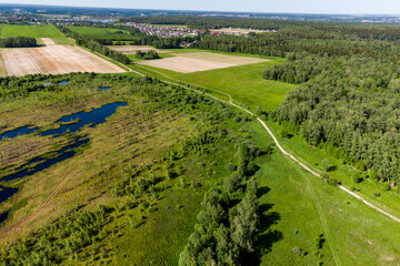 Aerial view of a country road going through fields and marshland, a picturesque aerial landscape