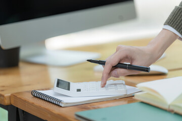 Close-up portrait of businesswoman accountant using calculator and laptop for matching financial data saving in office room, Business financial, tax, accounting concept.