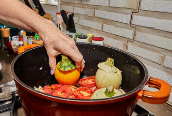 Stuffed zucchini and peppers are cooked in a saucepan on a gas stove