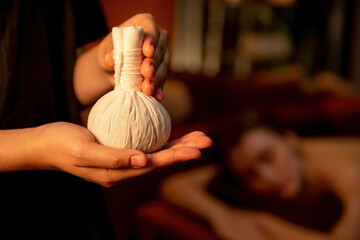 Hot herbal ball spa massage body treatment with masseur's hand hold or show herb bag at spa....