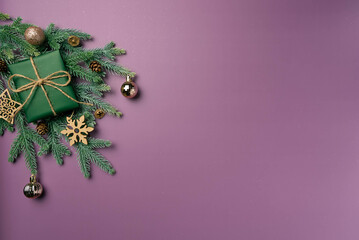 Christmas flat lay on a purple background with fir branch, balls and box