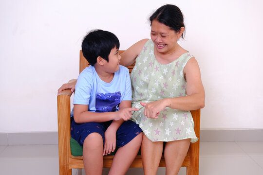 Chubby little boy playing with his grandma on an armchair