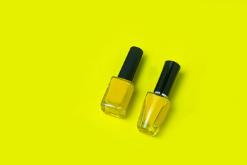 Two bottles of yellow nail polish in a glass bottle with a black cap, arranged in a horizontal...