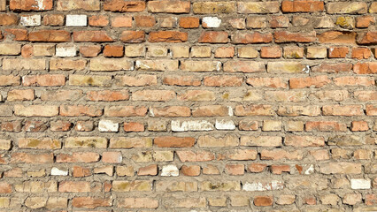 The texture of dilapidated brickwork. The wall is made of old shabby red brick