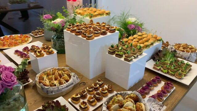 Table with a variety of appetizers and tapas of different flavors such as chicken, meat, roast beef and baos.