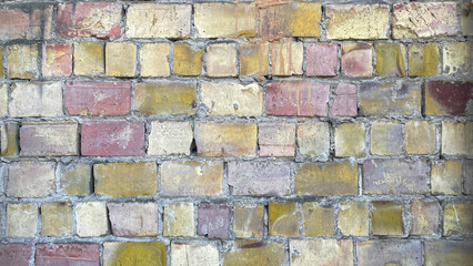 Close-up of a wall made of multicolored bricks of different sizes. The background is made of old dilapidated brick.
