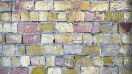 Close-up of a wall made of multicolored bricks of different sizes. The background is made of old...