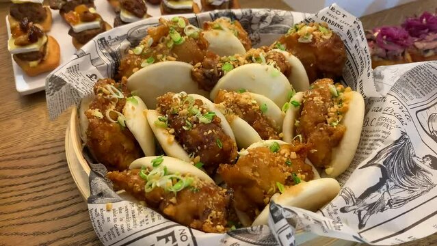 Breaded chicken baos with chopped chives on an appetizer table. Close up.