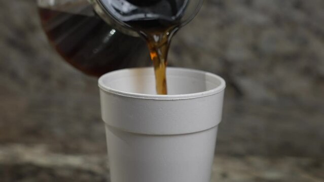 A man pours coffee into a styrofoam cup.