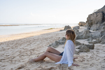 Young woman sitting on the beach alone, relax and enjoy nature