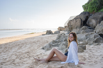 Fototapeta na wymiar Young woman sitting on the beach alone, relax and enjoy nature