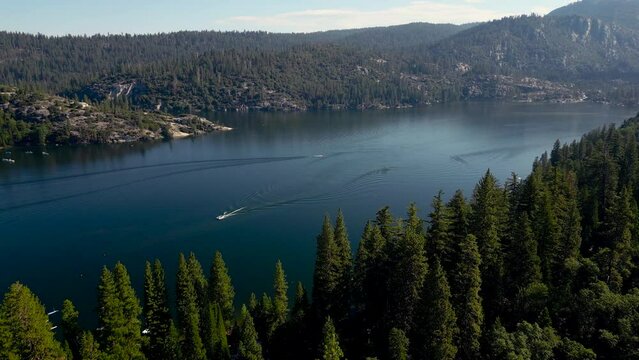 4k drone footage over Pinecrest lake in Pinecrest, California. With beautiful blue water with boats on it and pine trees surrounding the lake